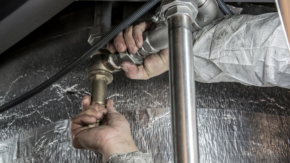 Plumber hands installing steel pipe fittings on a heating line